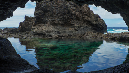 Crystal clear waters of the secluded Charco Azul volcanic cave, a natural turquoise pool created by the flowing lava and isolated by rocks from Atlantic Ocean, in  El Hierro, Canary Islands, Spain