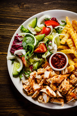 Kebabs - grilled meat with french fries and vegetables on wooden background