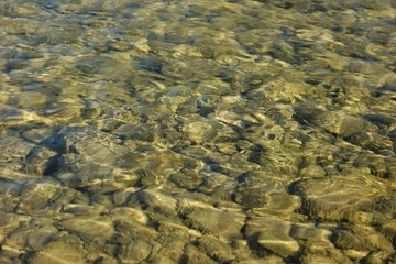 Pebbles under water in the rays of the sun, a mountain river, background