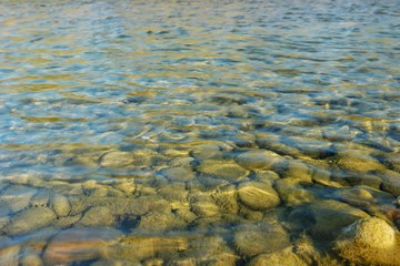 Pebbles under water in the rays of the sun, a mountain river, background