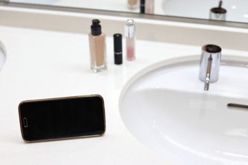 洗面でメイクをする　リキッドファンデーション、リップスティック、スマートフォン