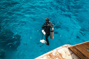 scuba diver sit on the yacht and ready to dive.
