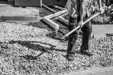 black and white picture of construction worker holding showel with gravel