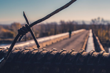 Lonely man behind barbed wire on the bridge