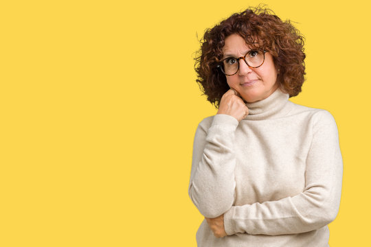 Beautiful middle ager senior woman wearing turtleneck sweater and glasses over isolated background with hand on chin thinking about question, pensive expression. Smiling with thoughtful face