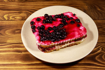 Tasty cheesecake with black currant on wooden table