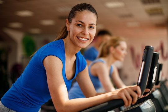 Young woman and man warming up on bikes in the gym