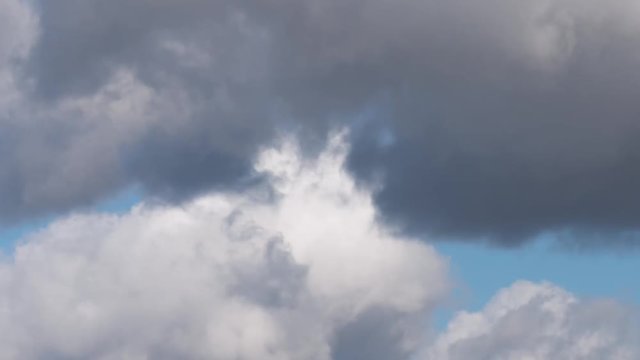 Time Lapse - beautiful white and grey fluffy clouds soar over a deep blue background. Cloudscape with autumn dark storm clouds moving fast over blue sky day - close-up.