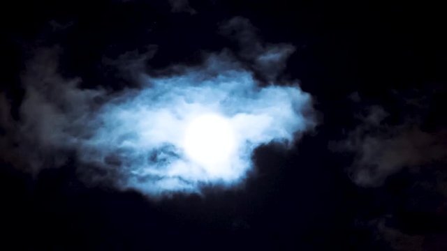 Time lapse - clouds passing by moon at night. Full moon at night with clouds. Beautiful nightly spooky background.