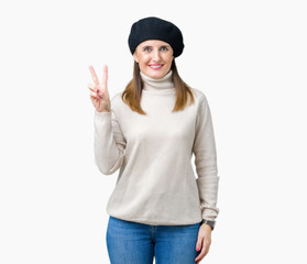 Middle age mature woman wearing winter sweater and beret over isolated background showing and pointing up with fingers number two while smiling confident and happy.