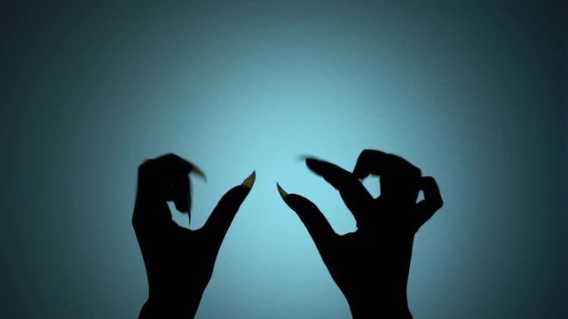 Dark monster hands with sharp nails horrifying victim, eerie horror silhouette. Blood-chilling horror thriller shot