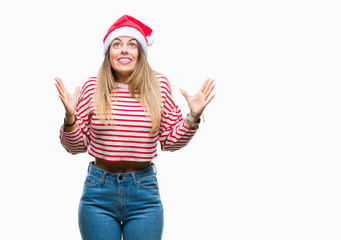 Obraz na płótnie Canvas Young beautiful woman wearing christmas hat over isolated background crazy and mad shouting and yelling with aggressive expression and arms raised. Frustration concept.