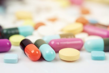 close up macro Pill spilling out disrupted. colorful pills capsule on to surface tablets on a table wooden background. drug medical healthcare concept.
