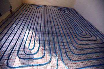 Laying blue pipes for floor heating at the construction site.