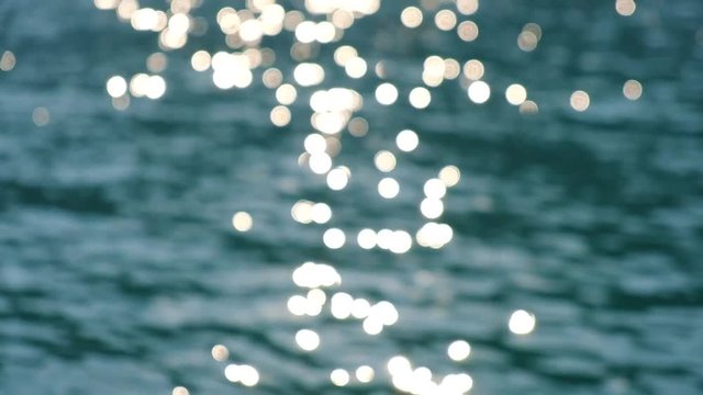 Sparkling bright wavy water shining at sunny summer day in slow motion. Abstract blurry background of seaside