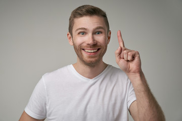 Fototapeta premium A smart scientist gets a new idea about the development, raises a finger to the fore, ready to start working on the project, confident in success. Excited expression, happy to get good idea