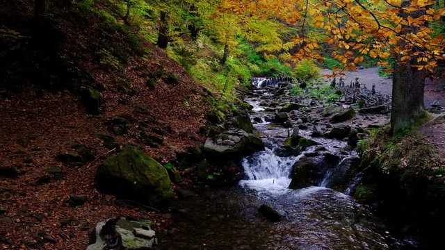 Tranquil waterfall scenery in the middle of autumn forest. Autumn forest creek