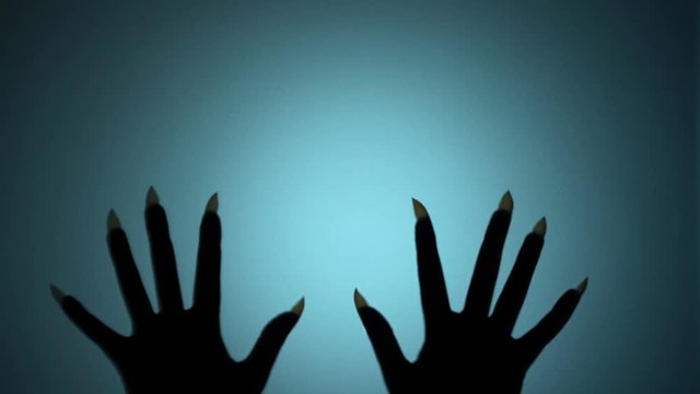 Witch hands with long sharp nails scratching glass, horrifying scene, creepiness. Blood-chilling horror thriller shot