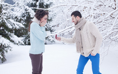 Man showing an engagement ring diamond to his amazed girlfriend in a winter park outdoor in the background. Proposal concept © maryadam
