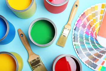 Flat lay composition with paint cans, brushes and color palette on blue background