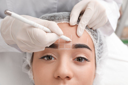 Young woman getting prepared for procedure of permanent eyebrow makeup in tattoo salon, closeup