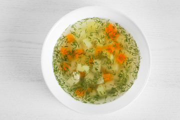 Bowl of fresh homemade soup to cure flu on wooden background, top view