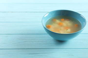 Bowl of fresh homemade soup to cure flu and space for text on wooden background