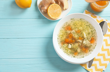Flat lay composition with bowl of fresh homemade soup to cure flu and space for text on wooden...