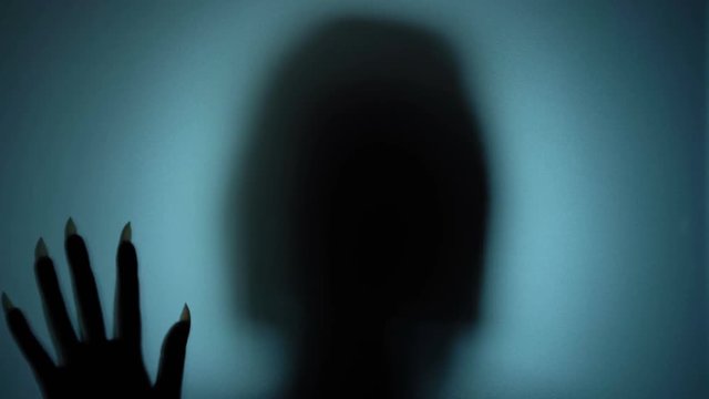 Ghostly woman in a haunted place, silent shadow behind glass, horror scene. Blood-chilling horror thriller shot