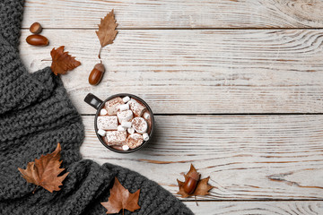 Flat lay composition with hot cozy drink and autumn leaves on wooden background. Space for text