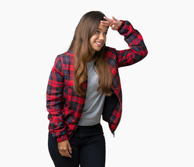 Young beautiful brunette woman wearing a jacket over isolated background very happy and smiling looking far away with hand over head. Searching concept.