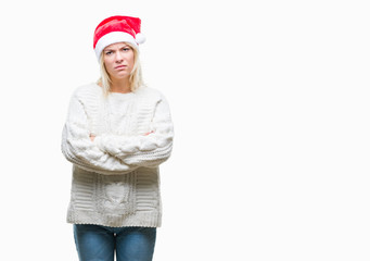 Young beautiful blonde woman wearing christmas hat over isolated background skeptic and nervous, disapproving expression on face with crossed arms. Negative person.
