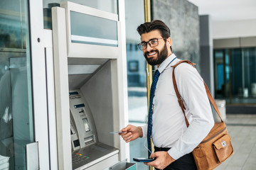 Naklejka na ściany i meble Businessman using card at an ATM