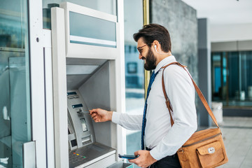 Businessman using card at an ATM - obrazy, fototapety, plakaty
