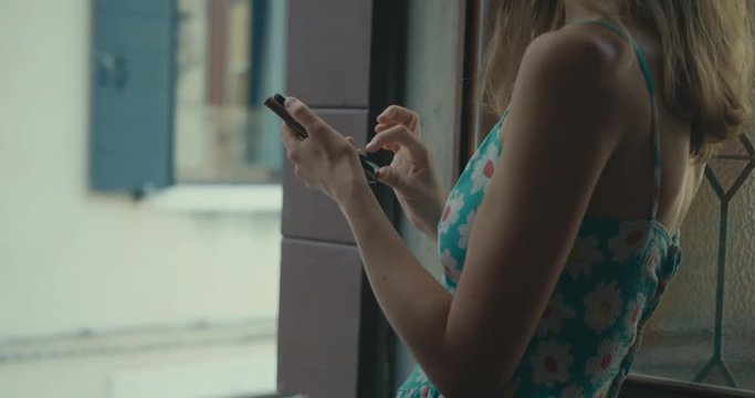Young woman using smartphone by the window