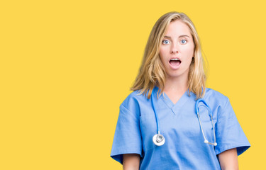 Beautiful young doctor woman wearing medical uniform over isolated background afraid and shocked with surprise expression, fear and excited face.