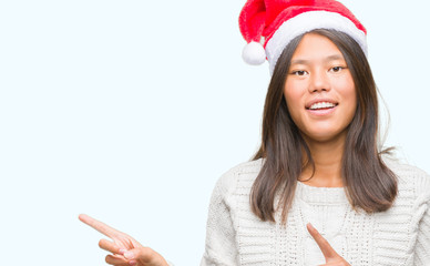 Young asian woman wearing christmas hat over isolated background smiling and looking at the camera...