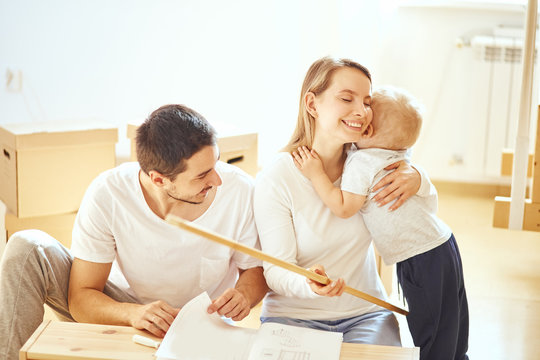 family with little boy assembling furniture at home, mother and son hugging after finishing assemble - Powered by Adobe
