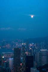 Fototapeta premium Full moon rise over Hong Kong Skyline at dusk. Modern China city with skyscrapers near the ocean