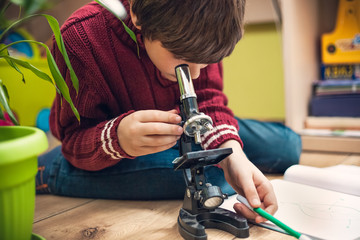 Closeup portrait of little boy using microscope on biology lesson - obrazy, fototapety, plakaty
