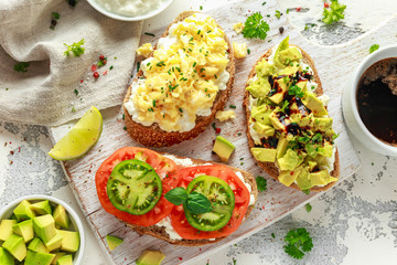 Vegetarian Healthy bread toasts with cottage cheese, heirloom tomatoes, scrambled eggs and avocado