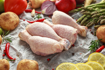 Raw Chicken drumstick on baking paper with variety of vegetables