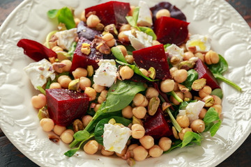Healthy Beet Salad with chickpeas, pistachios nuts, feta cheese on rustic wooden background
