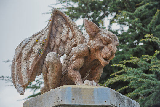 Image of a stone gargoyle sitting on top of a column with wings raised in San Martin de la Vega, Spain