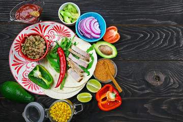 Tortillas flat and various vegetables for tacos or burrito making on rustic background, top view