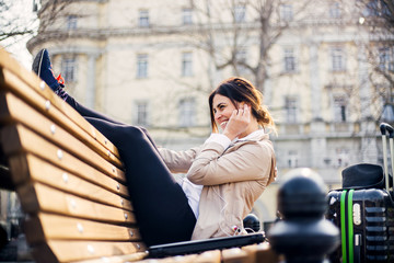 Traveling businesswoman sitting on the banch with bag and talking on mobile phone