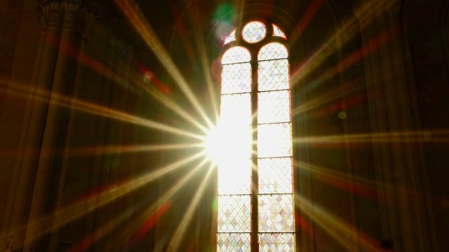 Sonnenstrahlen scheinen durch ein altes Kirchenfenster