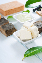 cosmetic clay, soaps, henna blocks, sponge and moisturizer on white wood table