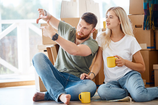 married couple sitting near cardboard boxes in new apartment relaxing after unpacking boxes