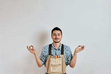 Satisfied carpenter meditating before work starts, with fingers folded in mudra gesture.